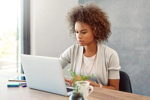 Shes in problem solving mode. a young woman working on a laptop at home. Foto stock