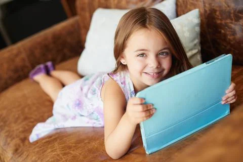 Shes a savvy little web browser. a little girl using a digital tablet at home. Stock Photos