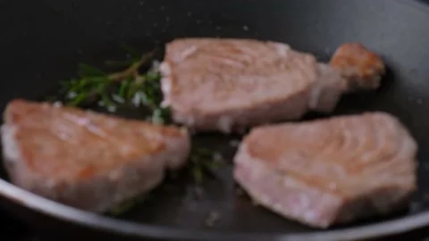Shift focus on cooking tuna steak with rosemary in a frying pan. close up Stock Footage 148049377
