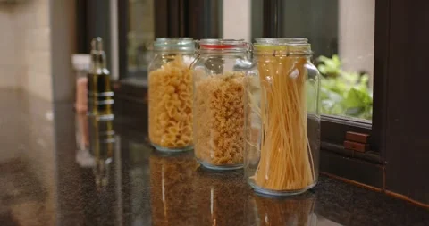 Shifting window light is causing focus shift, glass pasta jars are staying still Stock Footage 340256776