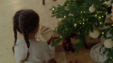 Сhild takes a gift from under a decorated Christmas tree Stock Footage 321682872