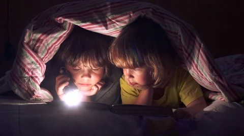 Сhildren read a book under the covers Video stock 59901642
