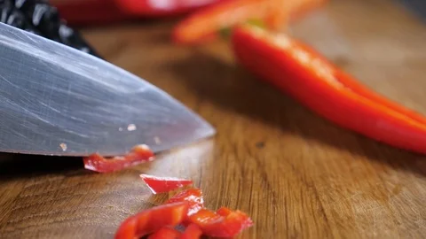 Сhili pepper is cut with a knife. Cutting red hot pepper on cutting board Stock Footage 86532402