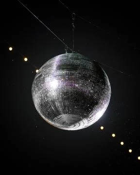 Shimmering disco ball, illuminated by a string of lights, hangs from a wire in a Foto stock