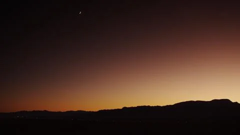 Shimmering freeway lights from distant traffic with a crescent moon at twilight. Stock Photos