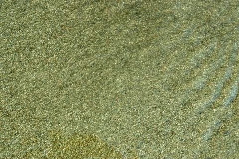 A shimmering, rippling surface with sunlight dancing on moving water over san Stock Photos
