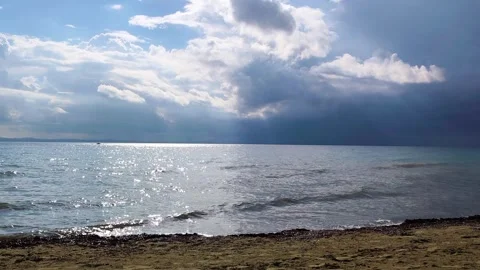 Shimmering Sea with Sun Rays Piercing Through Dramatic Clouds at the Beach Stock Footage 334819462