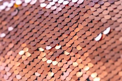 Shimmering sequin pattern in warm tones creating a textured surface 库存照片