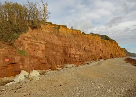 The shingle beach at Sidmouth in Devon with the red sandstone cliffs of the J 写真素材