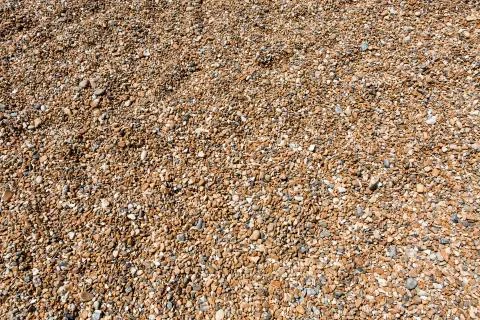 Shingle or stones on a beach washed up by the sea on a bright sunny day Stock Photos