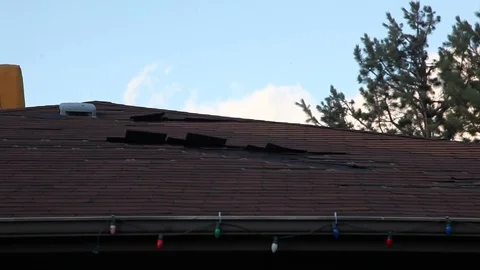 Shingles getting blown off of a roof in the middle of some strong winds. Video stock 103554419