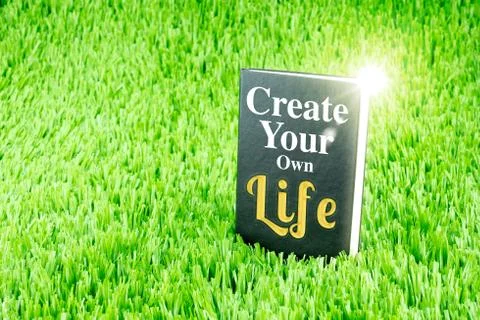 Shining Black book on grass with " Create your own life " word, Business and  Stock Photos