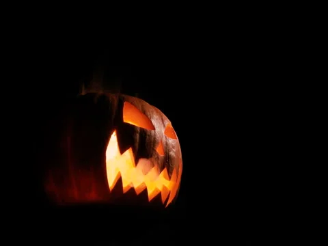 Shining Jack-O-Lantern. Halloween pumpkin with scary face isolated on the black Stock Footage 80142127