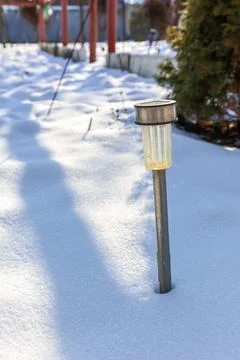 Shining light post standing tall amidst a blanket of gleaming snow in a ser.. Stock Photos