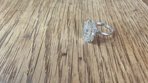 Shining oval diamond platinum ring close up on rustic wood surface Stock Footage 314895292