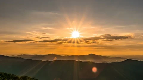 The shining sun disappears down the mountain ridge. Time lapse. Zoom out Stock Footage 145742695