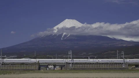 Shinkansen Passing Fields Beneath Snow Covered Mount Fuji and Clouds Vídeos de archivo 348353568