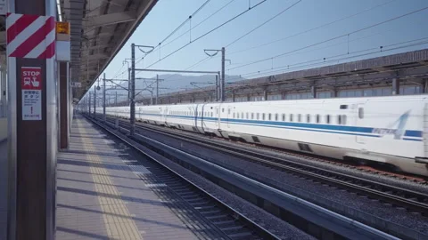 Shinkansen train passing through the Shin Fuji station at full speed Stock Footage 260979091
