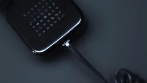 Shiny black handset with cable of old push-button telephone shines in darkness  Video stock 287958059