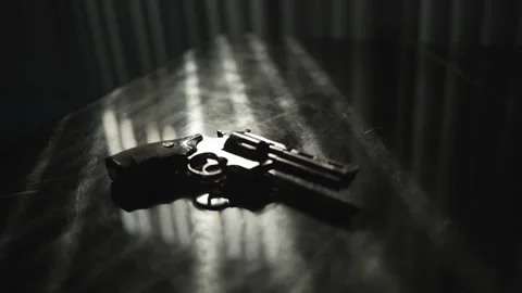 Shiny black revolver on a black table backlight by dramatic sunlight through the Vídeo Stock 290823720