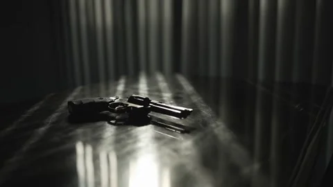 Shiny black revolver on a black table backlight by dramatic sunlight through the Vídeo Stock 291919079