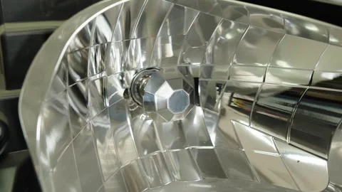 A shiny chrome reflector inside a disassembled car headlight close up Stock Footage 339686621