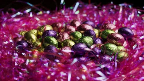Shiny colorful chocolate Easter eggs in pink plastic grass 動画素材 327909906
