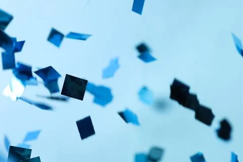 Shiny confetti falling down on light blue background Stock Photos