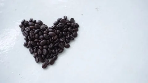 Of shiny dark roasted coffee beans scattered on a white surface Stock Footage 344704882