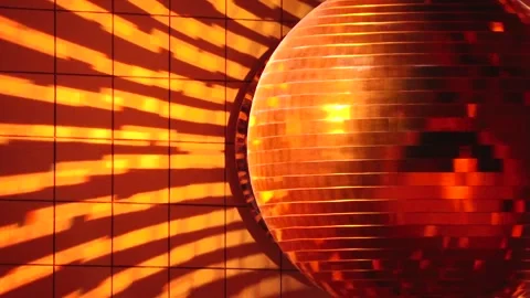 Shiny disco ball reflecting warm golden light and casting dynamic striped Stock Footage 330606735