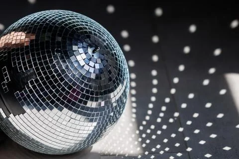 Shiny disco ball reflects light on dark surface Stock Photos