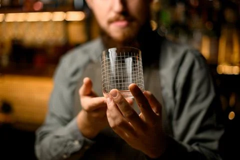 Shiny empty transparent glass with pattern in the hands of male bartender 스톡 사진