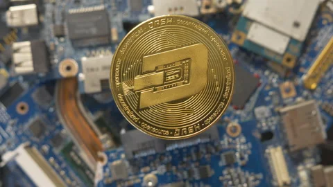  A shiny gold Dash cryptocurrency coin sitting atop a computer circuit board.  Stock Footage 342038438