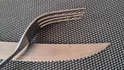 Shiny metal fork resting on a sharp serrated steak knife blade Stock Photos