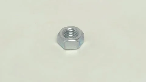 A Shiny Metal Nut strategically placed on a White Surface for enhanced Видео 283458309