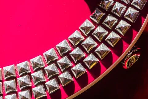 Shiny metallic studs in linear pattern on red background 스톡 사진