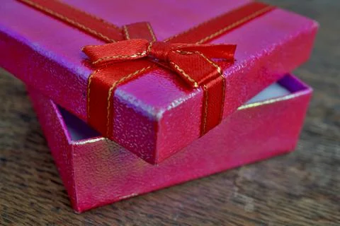 Shiny opened pink gift box with red ribbon and golden stitching Stock Photos