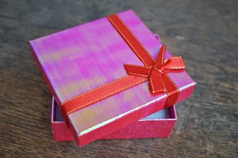 Shiny opened pink gift box with red ribbon and golden stitching Stock Photos