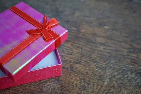 Shiny opened pink gift box with red ribbon and golden stitching Stock Photos