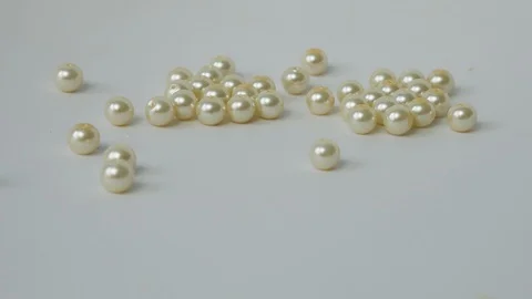 Shiny Pearl Beads Roll Down on a White Background. Beads Roll Side to Side Stock Footage 123073697