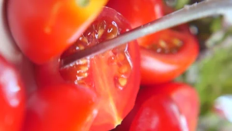 Shiny red cherry tomato being cut in half by knife in close-up dynamic moti.. Stock Footage 332211258