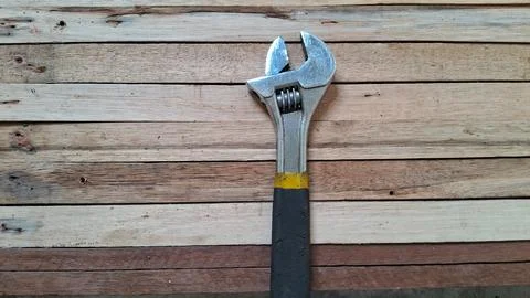 Shiny silver adjustable wrench resting on textured natural wooden planks Stock Photos