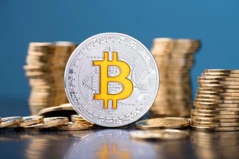 Shiny silver bitcoin with bit logo symbol and coins stacks on dark blue backg Foto stock