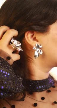 Shiny silver bow earring on model with matching ring, bold reflective accessory Stock Photos