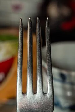 A shiny silver fork with four prongs resting on a table setting for elegant Stock Photos