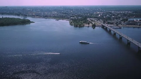 The ship and the boat are floating beside the bridge over the wide river Stock Footage 112552529