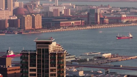 Ship approaching Kobe docks on blue sea. Japanese buildings in the foreground Stock Footage 130335083