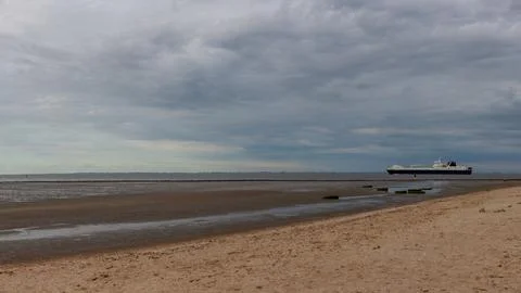 A ship on the beach at low tide with a cloudy sky. A derelict cargo ship st.. Stock Photos