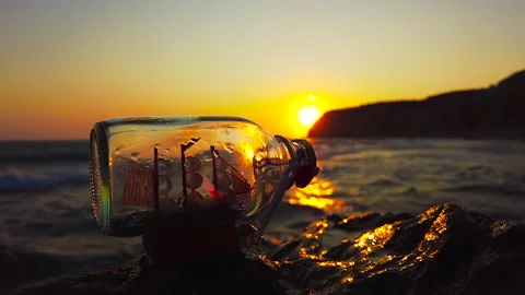 A ship in a bottle stands on a rock in front of a sunset Stock Footage 162081344
