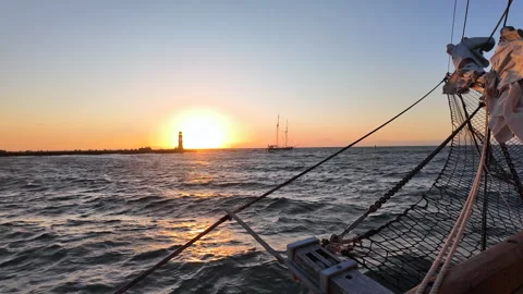 Ship bow pointing toward lighthouse and setting sun on sea horizon. Stock Footage 342131646